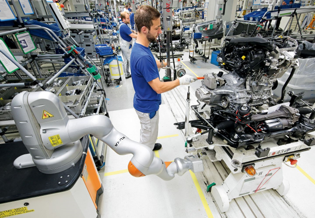 Automobilproduktion mit kollaborativem Roboter und Werker beim Zusammenbau eines Fahrzeugmotors in industrieller Umgebung